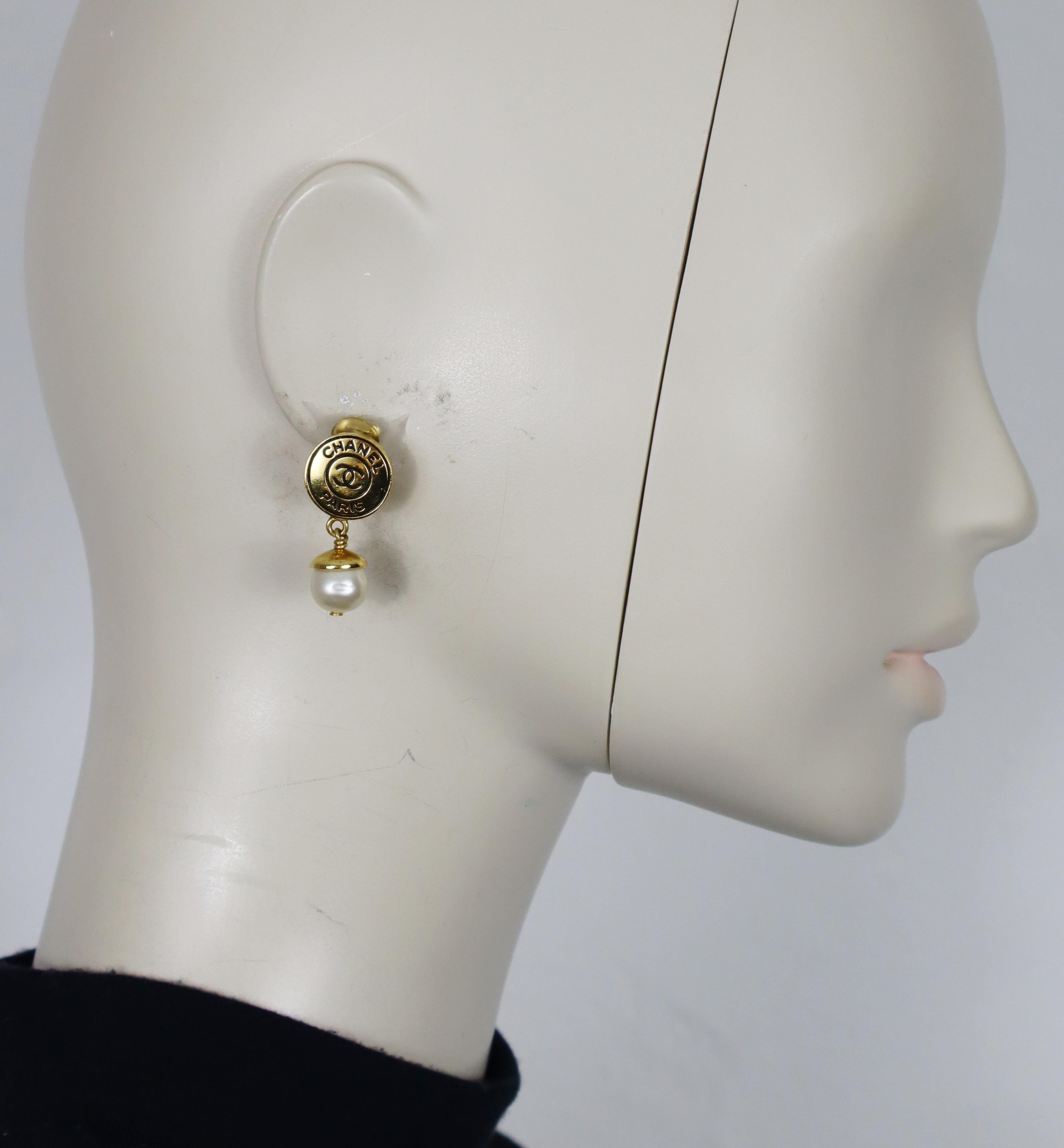 Pendientes colgantes CHANEL en tono dorado (de clip) con logotipo CC en la parte superior y una perla de imitación en la parte inferior.

Colección Primavera 1997.

Grabado CHANEL 97 P Fabricado en Francia.

Medidas orientativas: altura aprox. 3,3