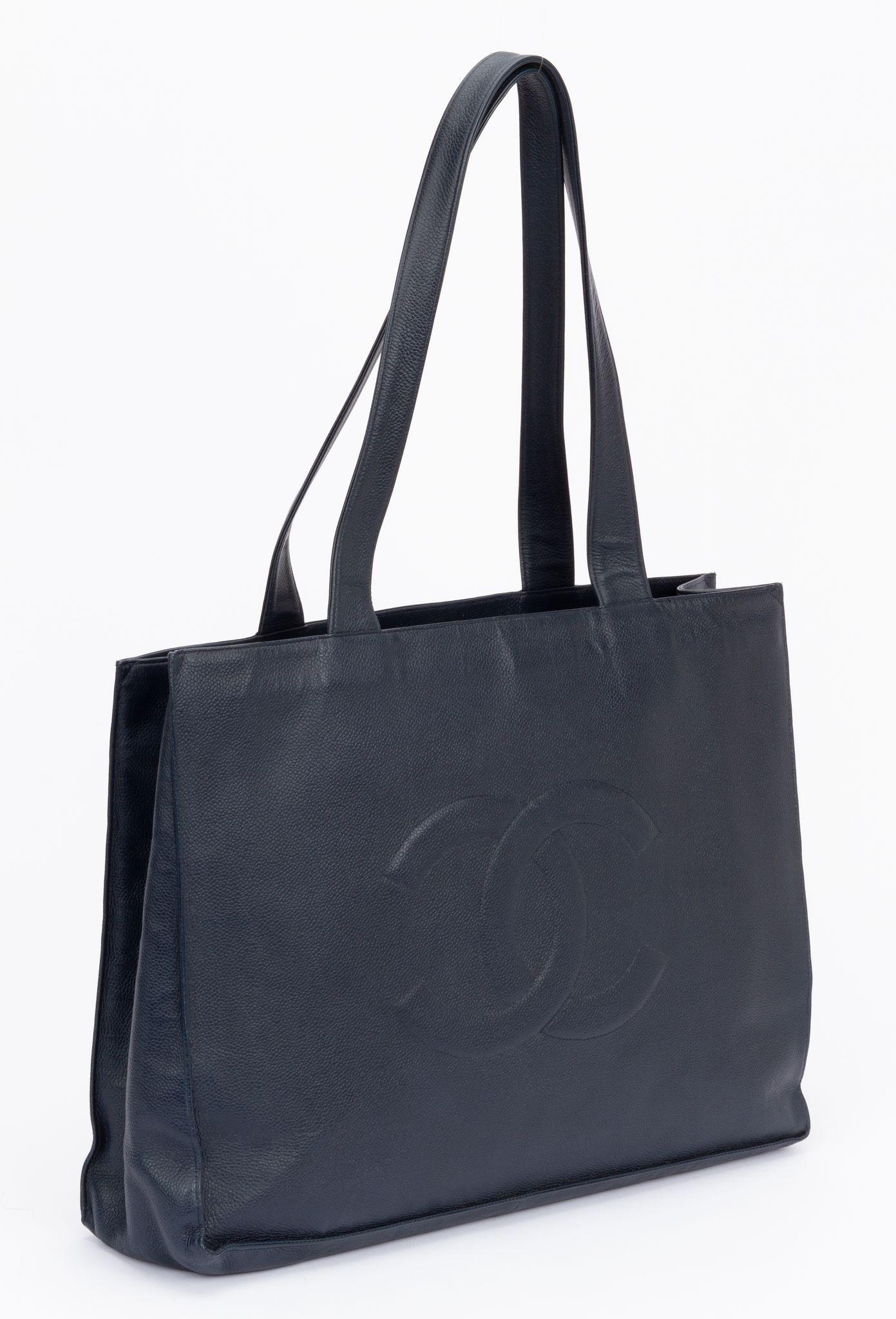 Chanel CC tote bag from the years 1998-2000. The interlocking CC motif has been a key cornerstone in collections for years. Made of navy caviar this tote bag is detailed with an embossed iteration of the signature logo. The handles have a drop of