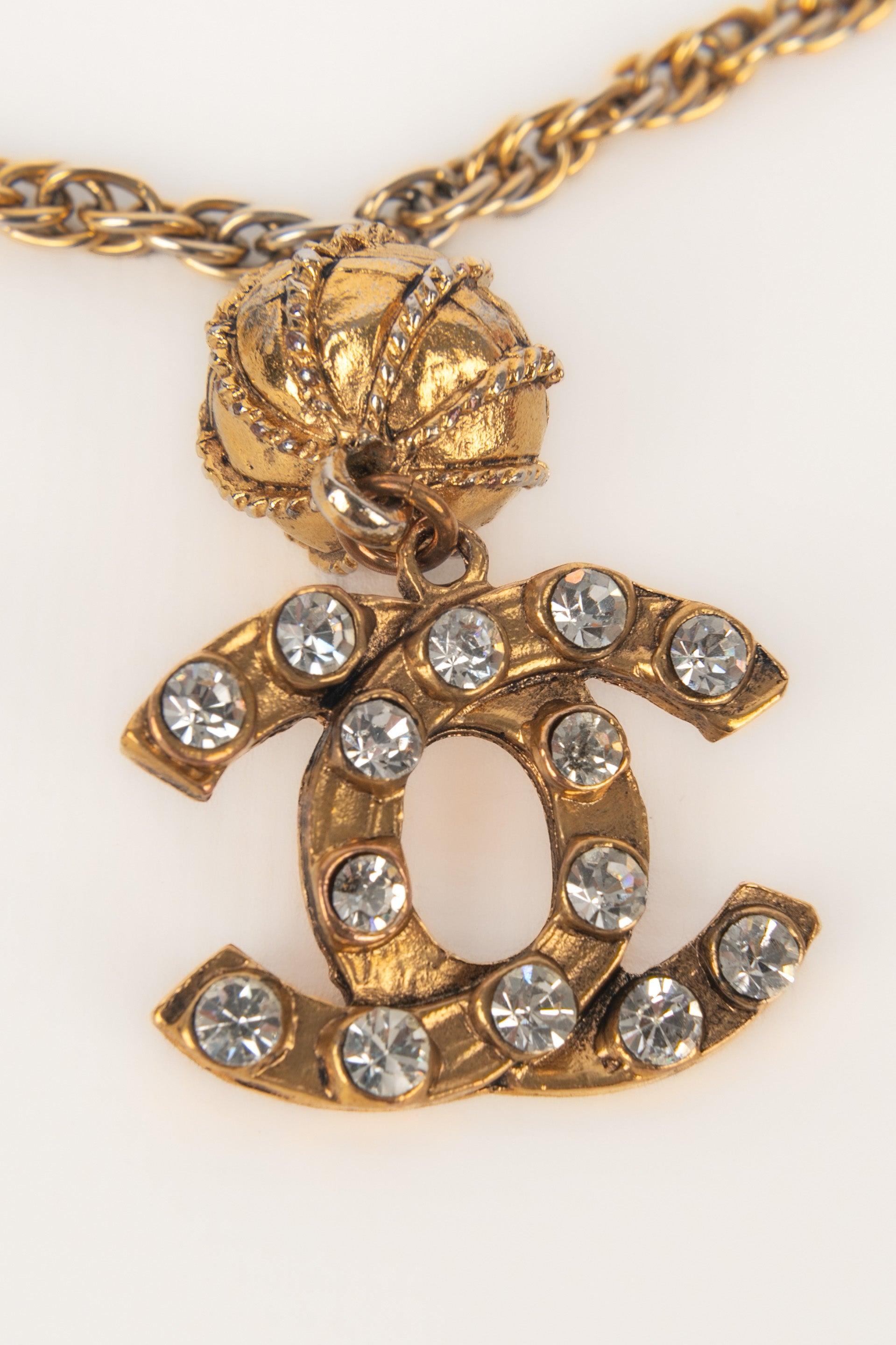 CHANEL - (Made in France) Golden metal necklace with a rhinestoned cc pendant. Jewelry from the mid-1980s.

Additional information:
Condition: Very good condition
Dimensions: Length: 90 cm

SKU:CB283