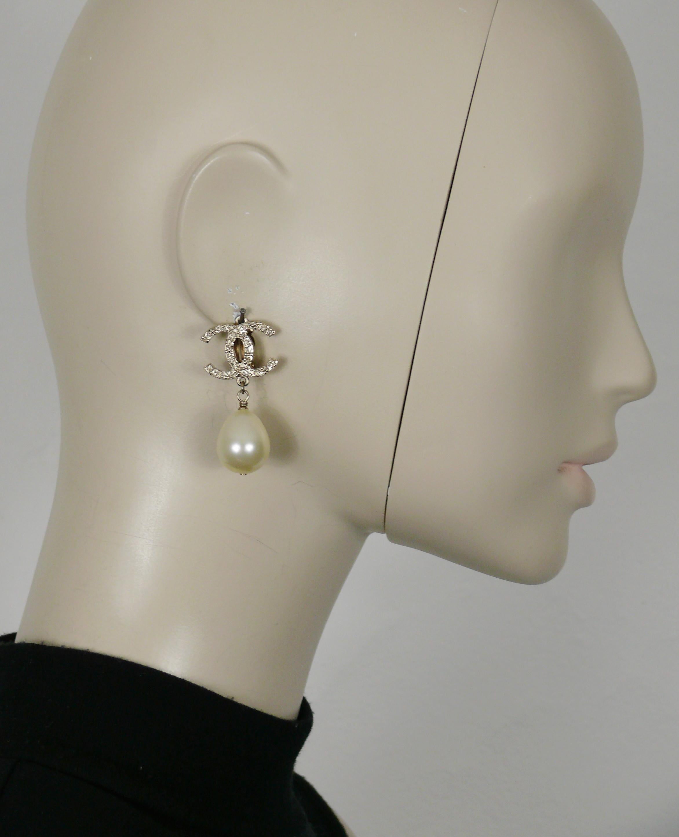 CHANEL pale gold tone CC logo dangling earrings featuring a large faux pearl drop.

Embossed CHANEL G12 A.

Indicative measurements : height approx. 4 cm (1.57 inches) / max width approx. 2.3 cm (0.91 inch).

Weight per earring : approx. 10