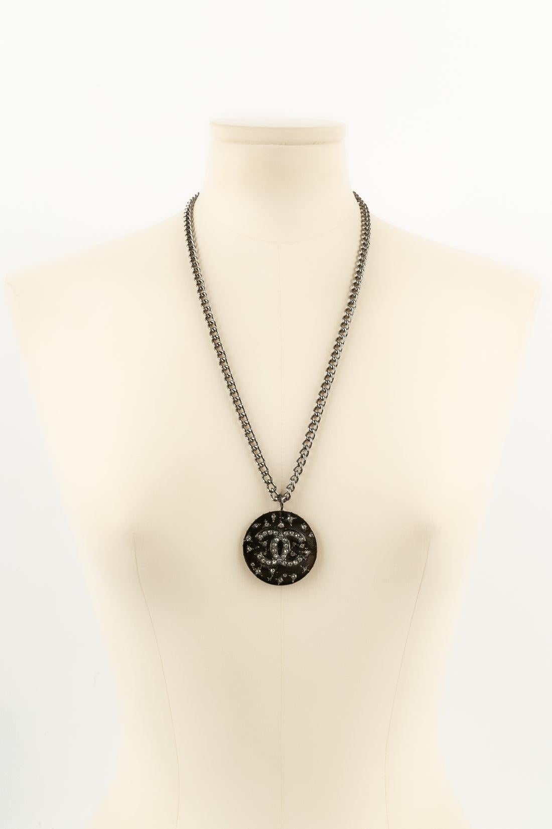 Chanel - Necklace in dark silver-plated metal with a cc pendant ornamented with Swarovski rhinestones. Unsigned jewelry from private sales.

Additional information:
Condition: Very good condition
Dimensions: Length: 64 cm

Seller Reference: CB14