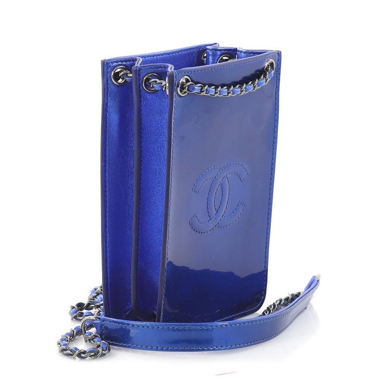 This Chanel CC Phone Holder Crossbody Bag Patent, crafted in blue patent leather, features woven-in leather chain strap with leather pad, front stitched CC detail, expandable sides, and gunmetal-tone hardware. It opens to a black fabric interior.