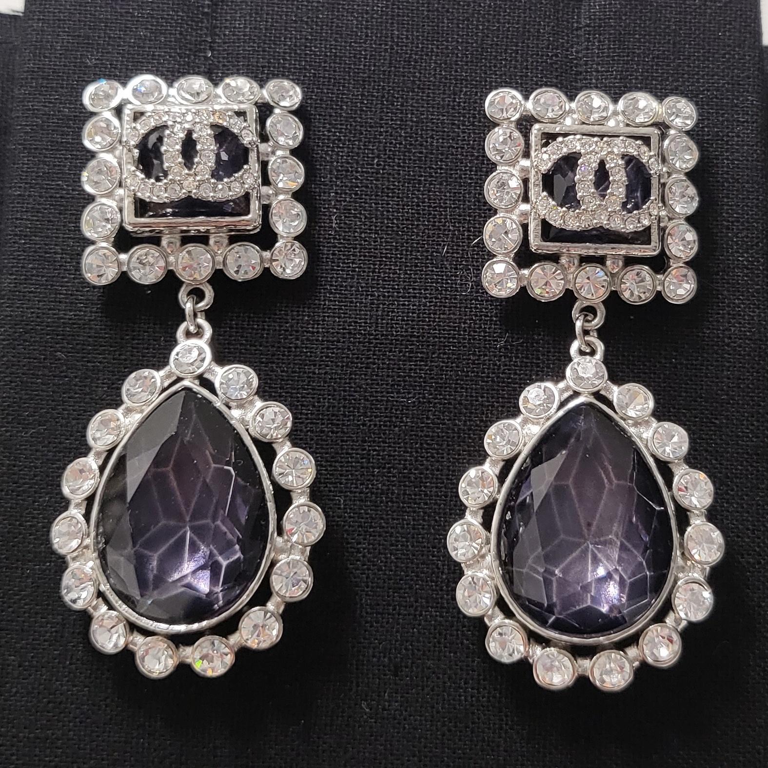 Introducing the epitome of elegance and sophistication: the Chanel CC Purple Drop Crystal and Rhinestone Silver Earrings. Crafted with meticulous attention to detail, these exquisite earrings are a testament to Chanel's legacy of timeless luxury and