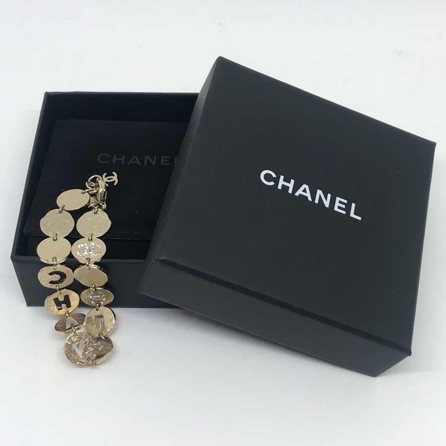 This CHANEL bracelet is made up of 13 hitting metal circles in golden color. The circles in the middle of the bracelet are perforated with the letters C, H, A, N, E, L. Four circles of the bracelet are strassed with a double C. The bracelet is