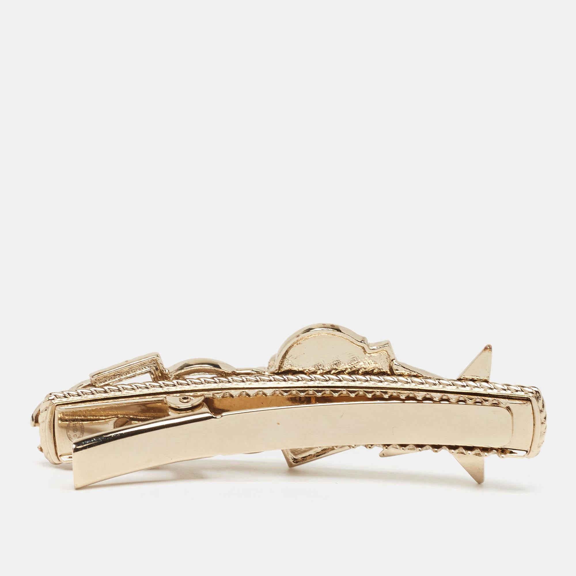 The Chanel hairclip features shimmering crystals and luxurious enamel on a gold tone base. This exquisite accessory combines the timeless charm of Chanel with modern flair perfect for adding a touch of refined beauty to any hairstyle. Its intricate
