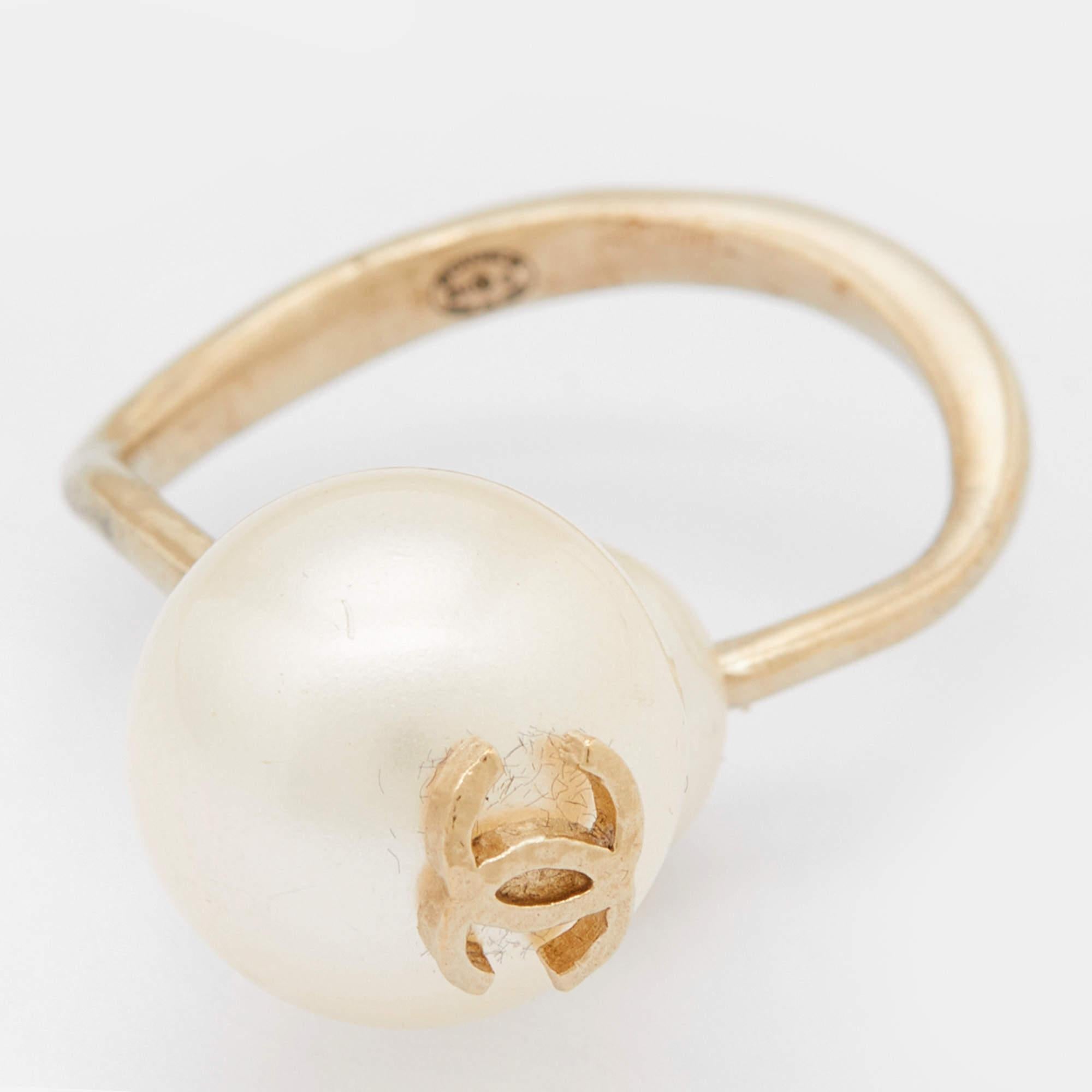 The ever-timeless CC logo remains the highlight of this creation, laid elegantly atop a large faux pearl. This Chanel ring with a bent gold-tone metal band is sure to be a favorite accessory.

