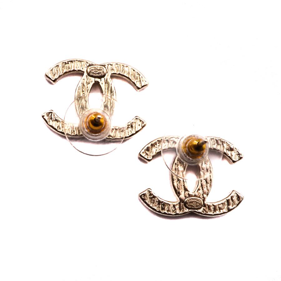 The pair of earrings is from Maison CHANEL. Each represents the CC emblem of the brand in striated metal and gilded with fine gold. They are part of the Métiers d'Arts Paris-New-York Fall / Winter 2019 collection.
The earrings are studs in perfect