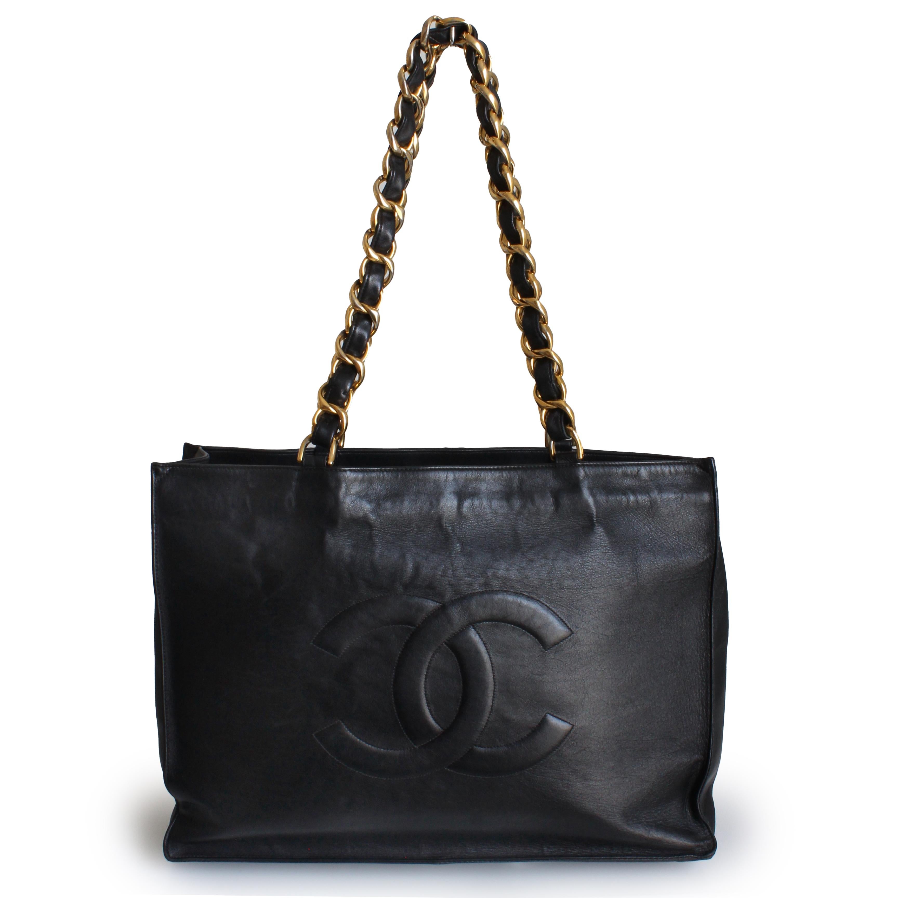 Authentic, preowned, vintage Chanel CC tote bag, likely made in the early 90s.  Made from black lambskin leather, it features an open top, Chanel's iconic CC logo stitched onto one side, chunky gold metal chain and leather straps and a cavernous