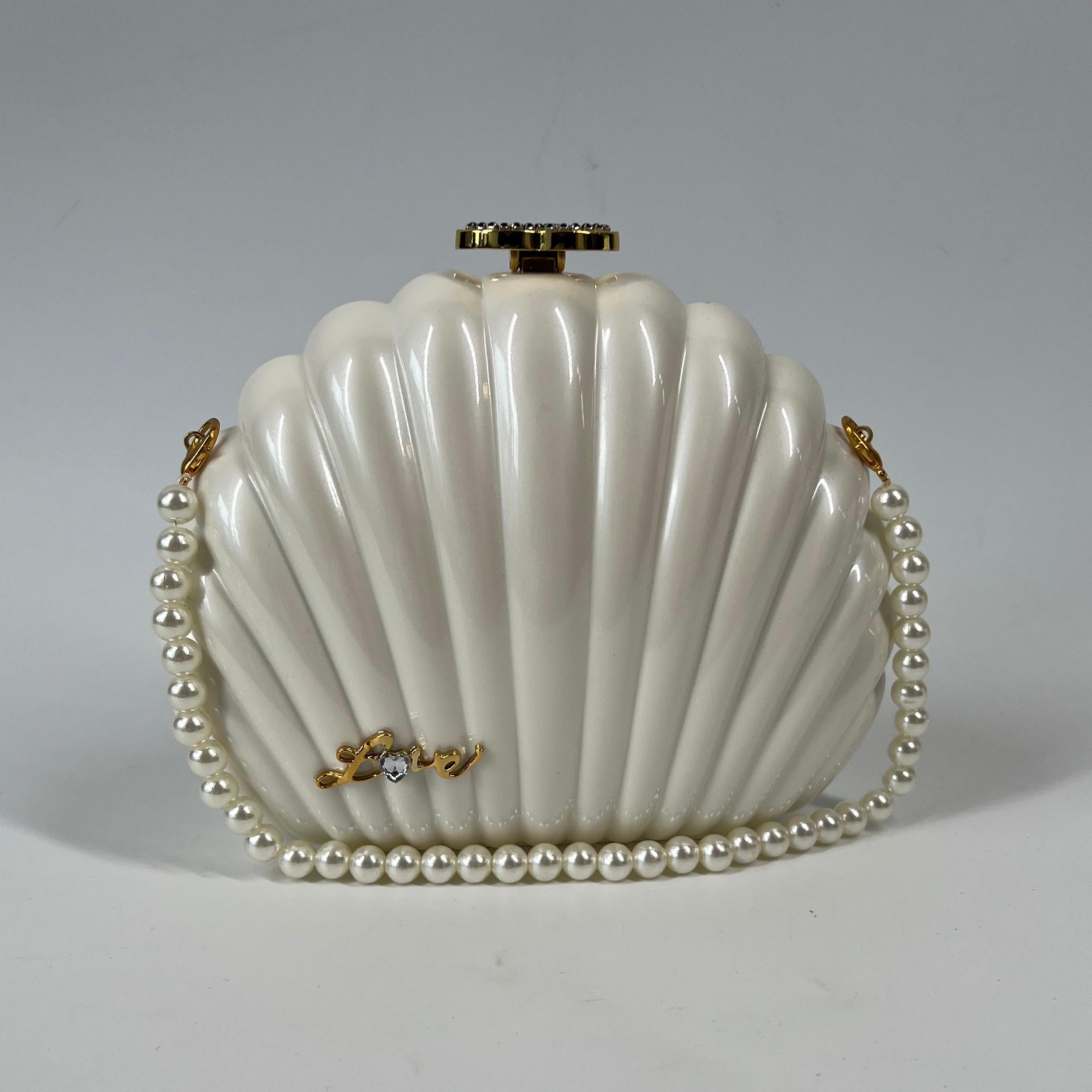 Collectible Chanel VIP gift with purchase bag. The bag takes the form of a sea shell.

COLOR: White
MATERIAL: PVC, strass CC, leather/chain strap
ITEM CODE: Gifted item with no hologram.
MEASURES: 6.5” x 9”
DROP: 21” (leather and chain) & 7” (faux