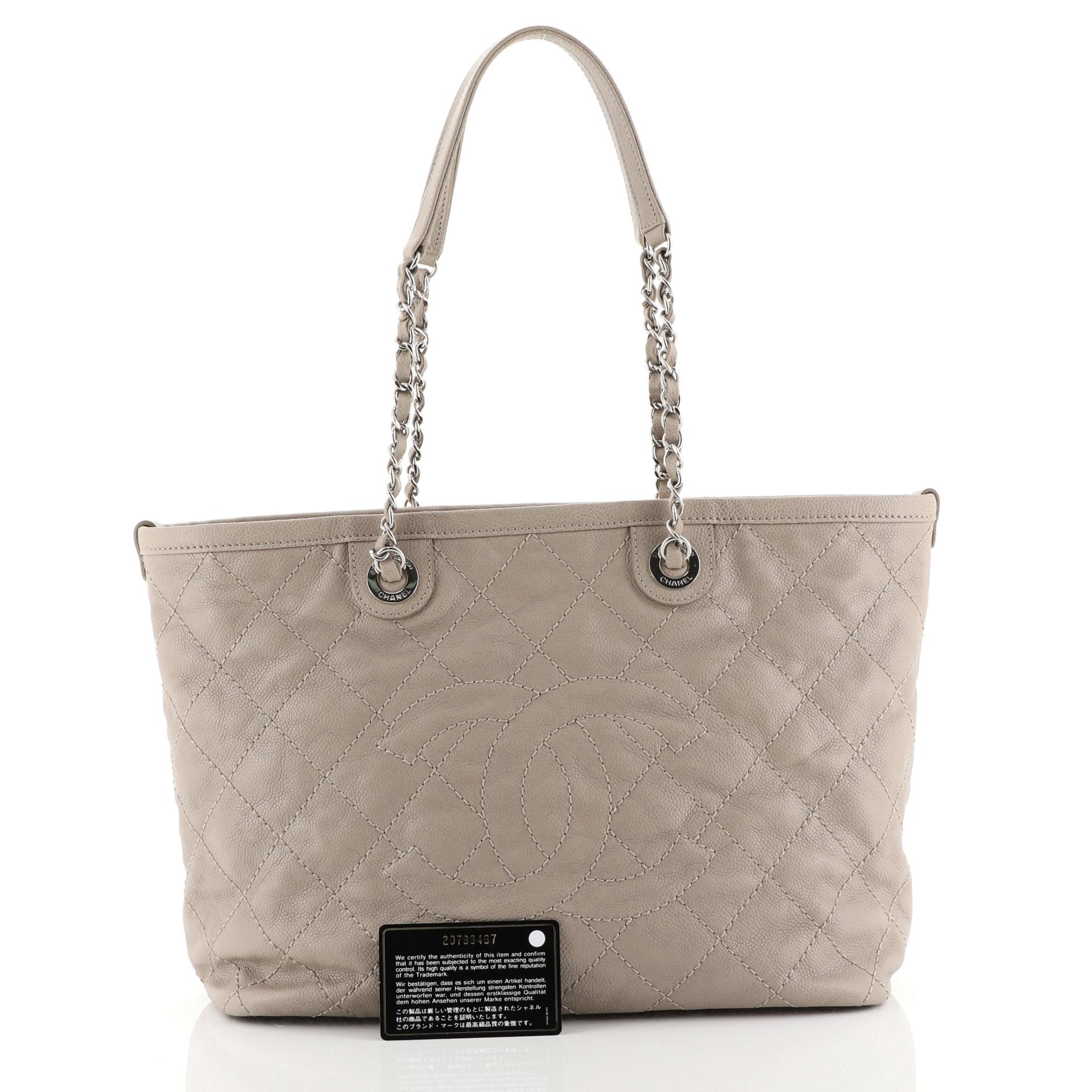 This Chanel CC Zip Tote Quilted Caviar Large, crafted in neutral quilted caviar leather, features woven-in leather chain straps with leather pads, stitched CC logo in the middle, protective base studs, and silver-tone hardware. Its zip closure opens