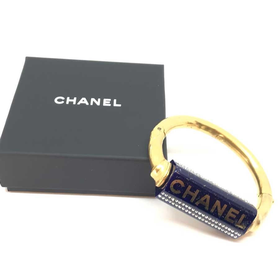 Le bracelet est de la Maison CHANEL. Elle représente une tige épaisse dorée à l'or fin qui comprend un tube en céramique bleue serti de strass.
Le bracelet n'a jamais été porté. Il provient de la collection automne-hiver 2019, comme l'indique son