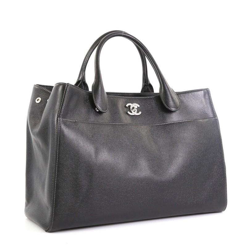 This Chanel Cerf Executive Tote NM Caviar Large, crafted from black leather, features dual-rolled tall handles, CC turn-lock closure, side snap buttons, and silver-tone hardware. Its CC turn-lock closure opens to a red fabric interior that includes