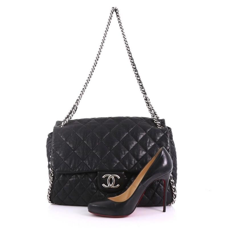 This Chanel Chain Around Flap Bag Quilted Leather Maxi, crafted from black quilted leather, features woven-in leather chain strap, chain-around trims, frontal flap with CC logo, and silver-tone hardware. Its magnetic snap closure on its flap opens