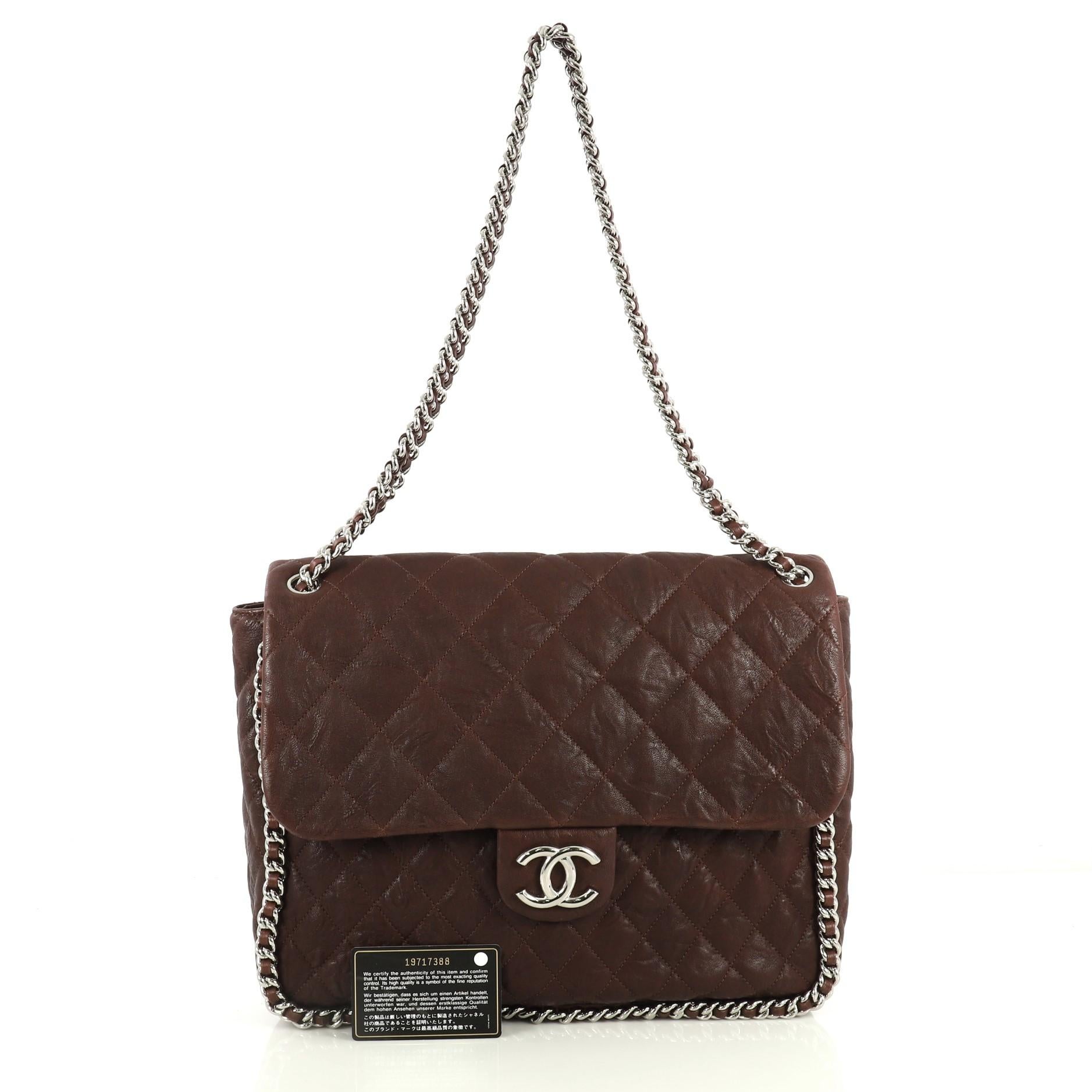 This Chanel Chain Around Flap Bag Quilted Leather Maxi, crafted in red quilted leather, features woven-in leather chain strap, chain-around design, frontal flap with CC logo, and chrome-tone hardware. Its magnetic snap closure opens to a gray fabric