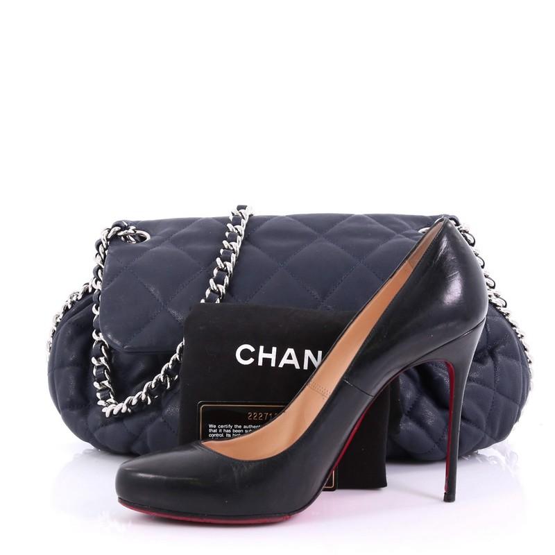 This Chanel Chain Around Flap Bag Quilted Leather Medium, crafted in dark blue quilted leather, features woven-in leather chain strap, chain-around design, frontal flap with CC logo, and silver-tone hardware. Its magnetic snap closure opens to a