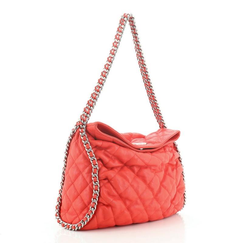 This Chanel Chain Around Hobo Quilted Washed Lambskin, crafted red quilted leather, features multiple silver woven-in leather chain straps wrapping around the bag, a large CC Chanel emblem, and silver-tone hardware. Its magnetic snap closure opens