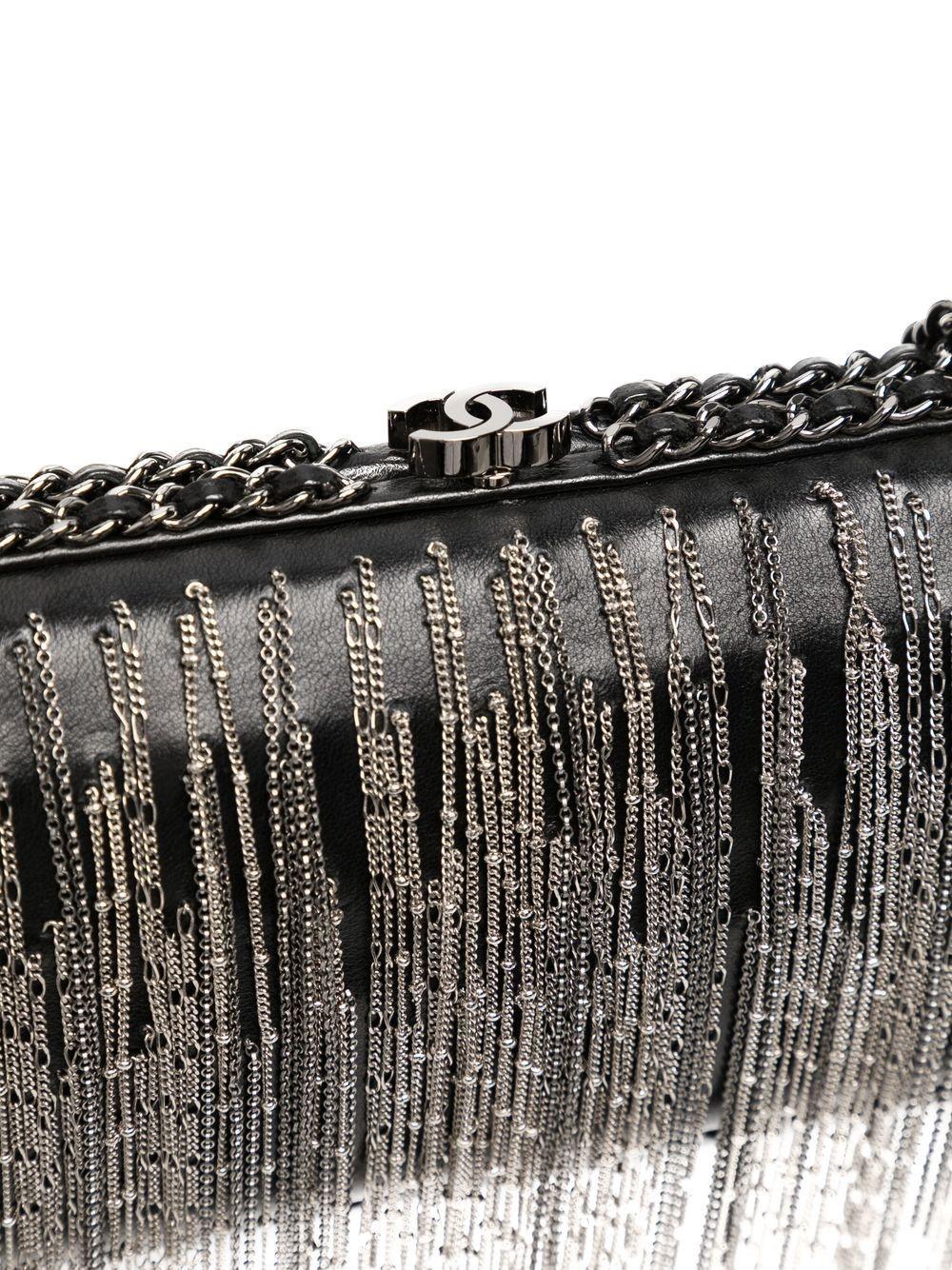 Diese kantige Clutch mit Kettendetails von Chanel stammt aus der Herbstkollektion 2017. Für diese Kollektion verwandelte Karl Lagerfeld das Grand Palais auf dem Laufsteg in eine Raumstation und setzte auf viel Schwarz, Silber und Glanz, was diese