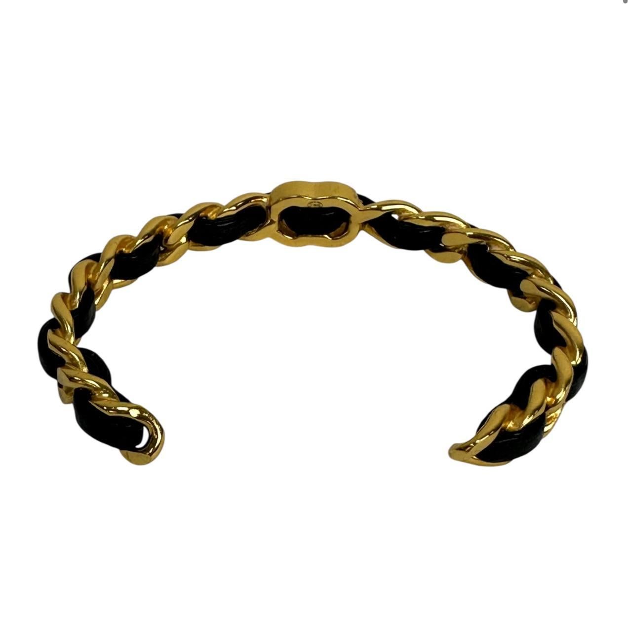 
A striking chain bracelet interwoven with black leather delivers a refined statement through contrast and texture. The glossy gold-tone metal paired with smooth leather adds depth and versatility. Whether styled with sleek tailoring or laid-back