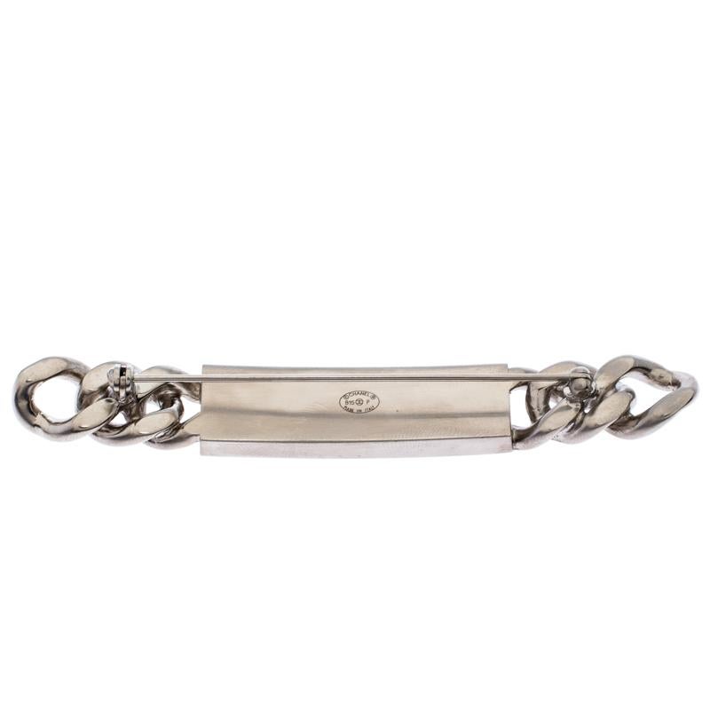 Chanel creations are a symbol of luxury and everything fine that ever existed. In a silver-tone body comes this brooch made in a bar-like shape with chain-link accents. It is detailed the brand logo engraving at the front. With a pin fastening at