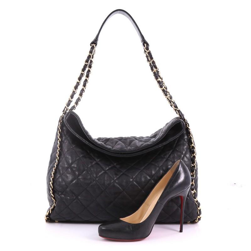 This Chanel Chain Me Hobo Quilted Leather Large, crafted from black quilted leather, features woven-in leather chain trims and straps with shoulder pad, CC logo on the sides and gold-tone hardware. Its magnetic snap closure opens to a black fabric