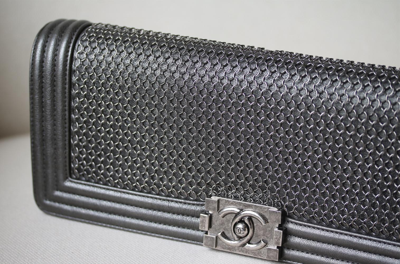 Chanel Metallic Chainmail and Leather Long Boy Clutch. Features metallic gunmetal-silver leather and chainmail detail. Gunmetal-silver hardware, and black fabric lining. Flap compartments. Zip interior pocket. Made in Italy. Does not come with a