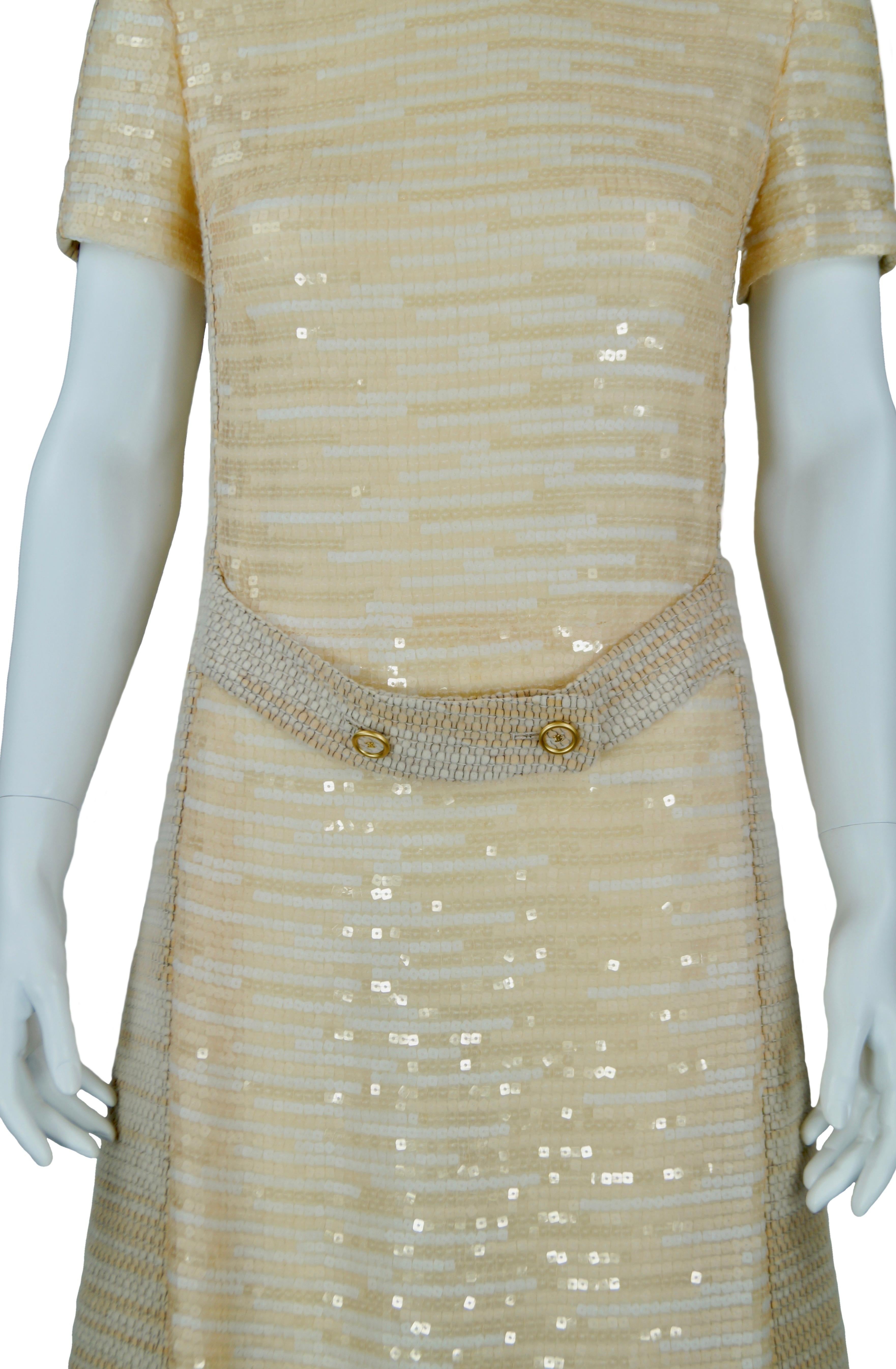 CHANEL dress F/W 2001 collection
A-line dress in beige melange tweed and champagne sequins; on the front  martingale belt with logo buttons; short sleeve; zip on the back.
Size Fr 40
Made in France
Measures:
Length cm. 98
Shoulders cm. 40
Bust cm.