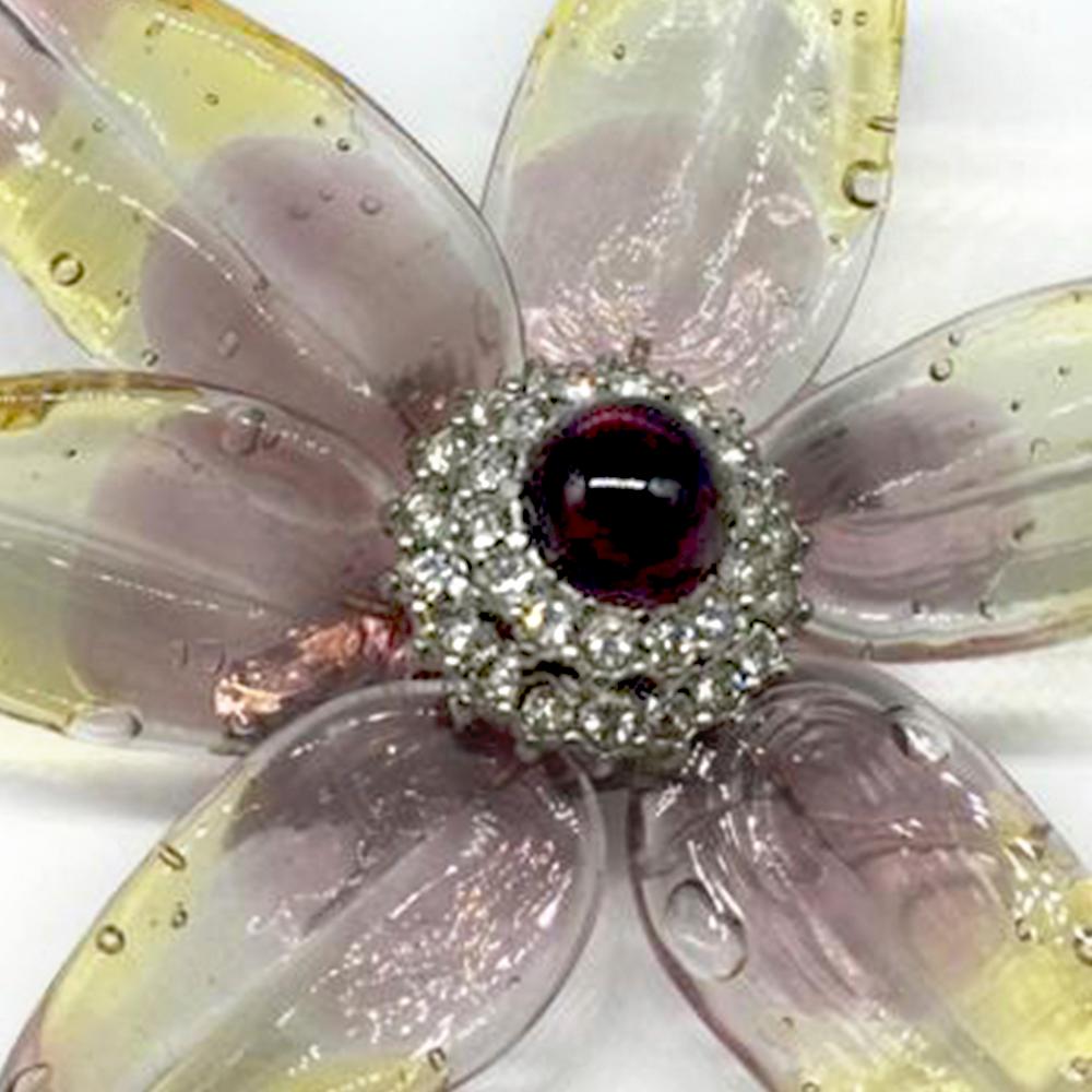 Crafted in France from an intricate combination of silver-plated metal and transparent resin in a spring-time palette of lilac and yellow, this vintage 1998 brooch from Chanel features a distinctive lily petal design, rhinestone embellishments