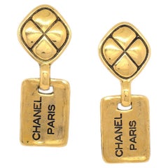 Boucles d'oreilles pendantes de soirée Chanel en métal doré avec logo « CHANEL PARIS »