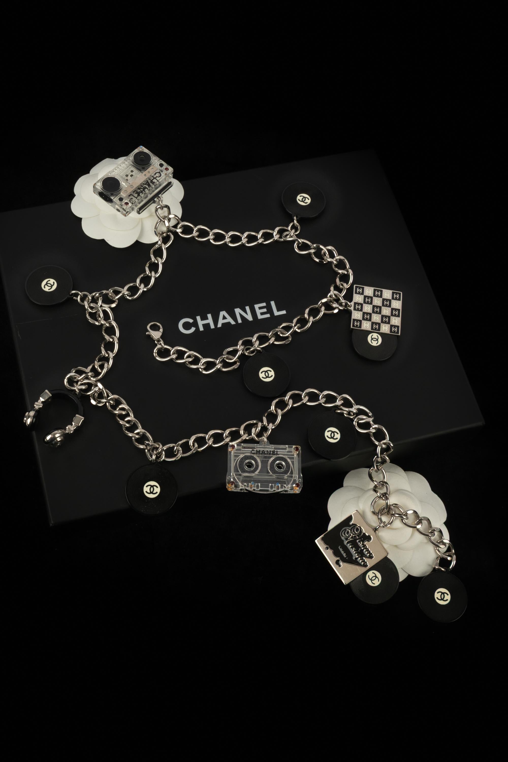 Chanel - (Made in France) Collana a catena argentata con charme in bachelite che rappresentano cuffie, musicassette o dischi in vinile. Collezione primavera-estate 2004 sotto la direzione artistica di Karl Lagerfeld.

Condizioni:
Ottime