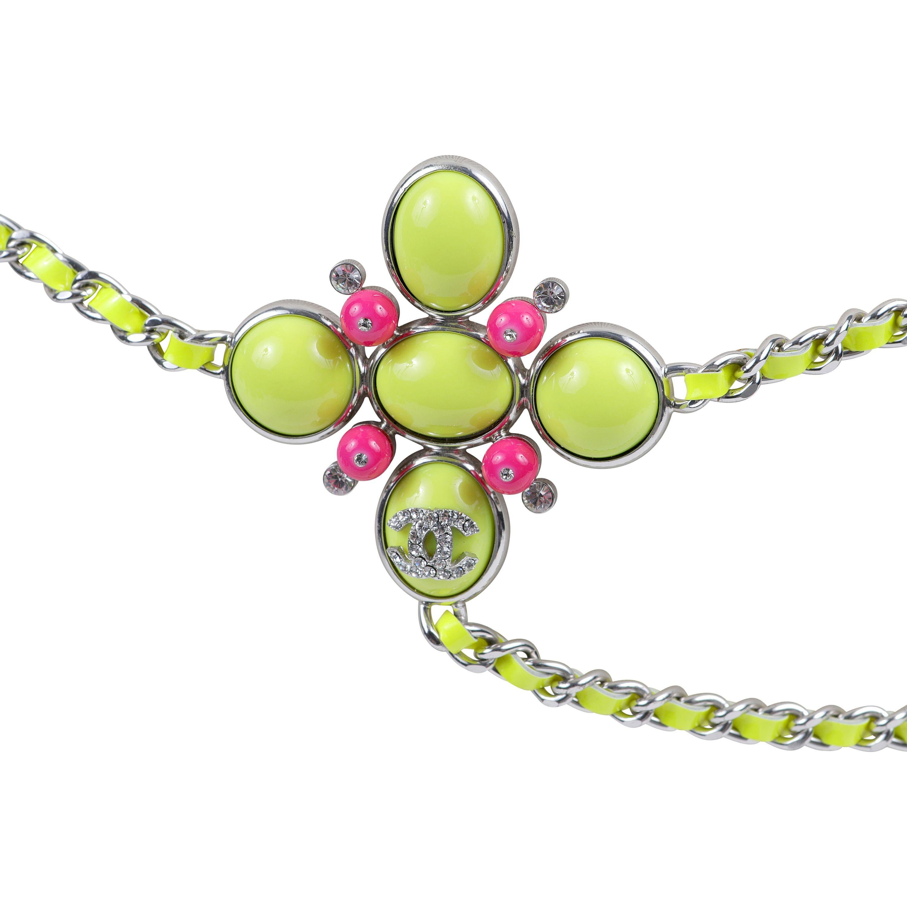 This authentic Chanel Chartreuse Green Patent Leather Chain Belt Necklace is pristine.  Nearly neon chartreuse green patent leather is entwined with silver chain.  Anchored with a resin “flower” brooch in green and vibrant pink with crystal CC.