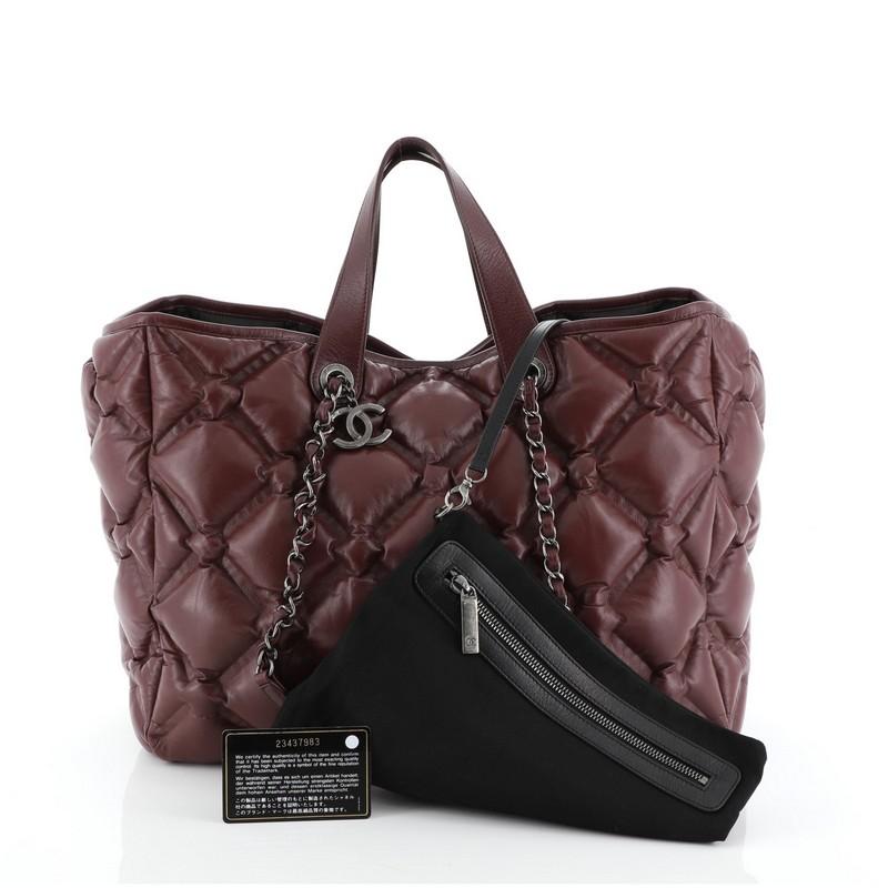 This Chanel Chesterfield Shopping Tote Quilted Leather Large, crafted in red quilted leather, features dual top leather handles, woven-in leather chain link straps, protective base studs, and aged silver-tone hardware. It opens to a black nylon