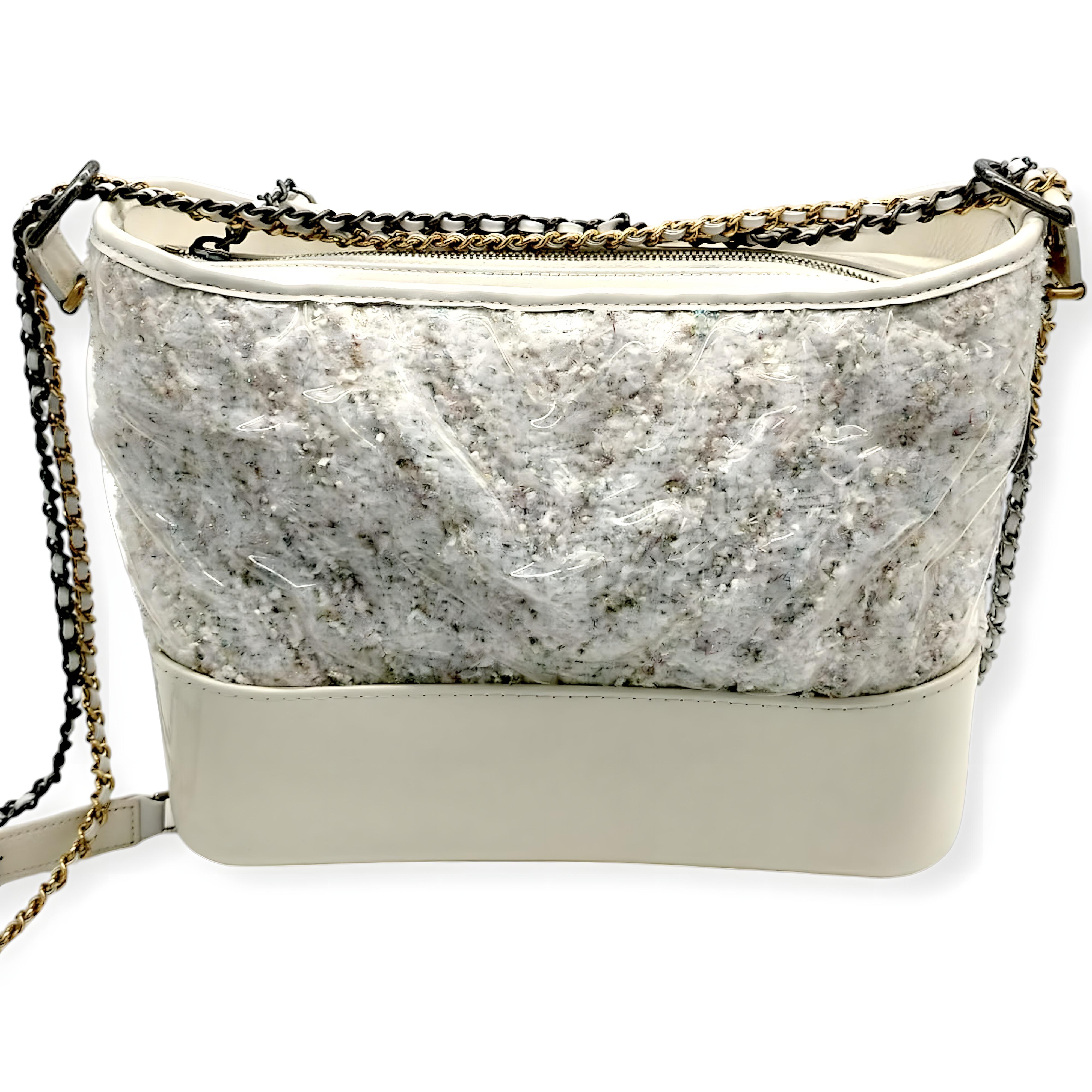 From 2018 collection, Chanel Gabrielle Hobo bag in white patent calfskin and PVC-coated tweed, accented with ruthenium, silver, and gold hardware. This sophisticated design features a 26-inch leather and chain strap that can be worn doubled, as well