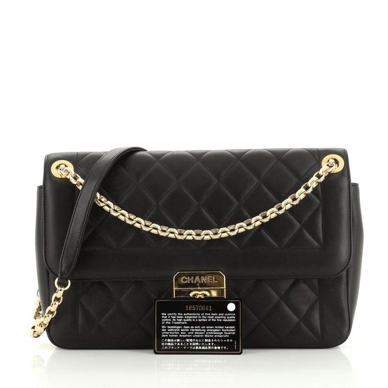 This Chanel Chic With Me Flap Bag Quilted Lambskin Large, crafted in black quilted lambskin leather, features chain link strap with leather pad and gold-tone hardware. Its press lock closure opens to a red leather interior with zip pocket. Hologram