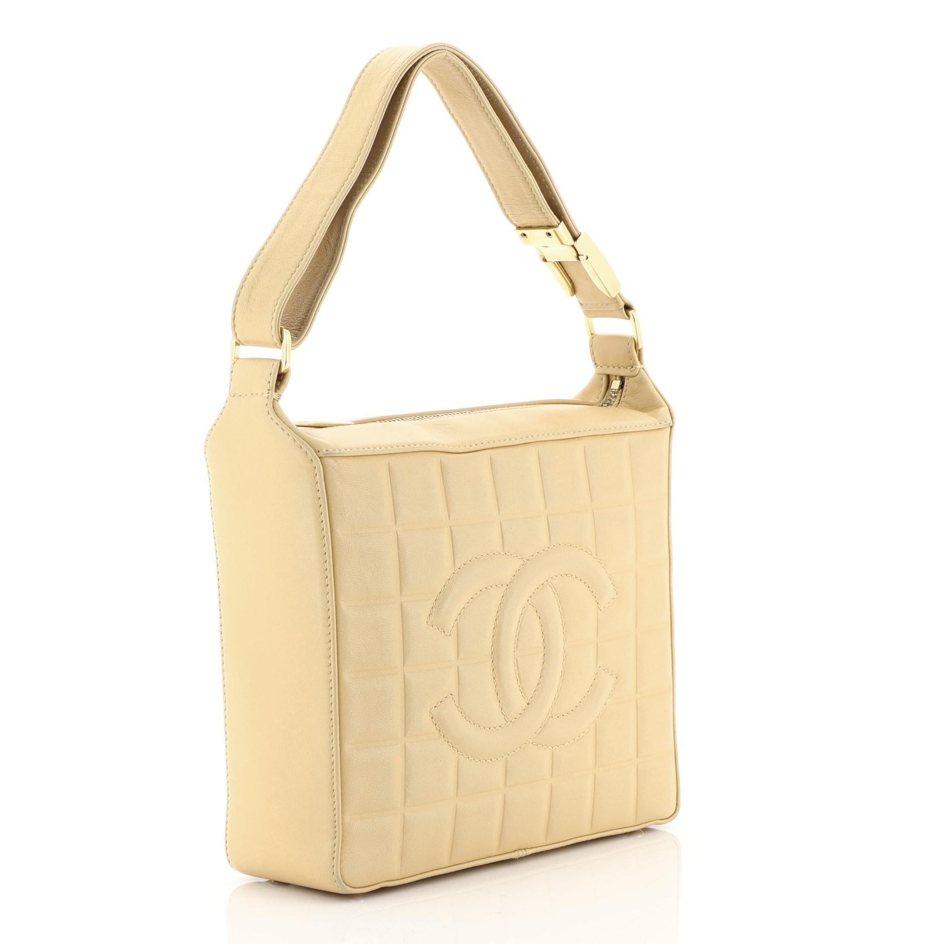 This Chanel Chocolate Bar CC Shoulder Bag Quilted Leather Small, crafted in neutral quilted leather, features long leather shoulder strap, square quilt design, and gold-tone hardware. Its zip closure opens to a neutral fabric interior with zip and
