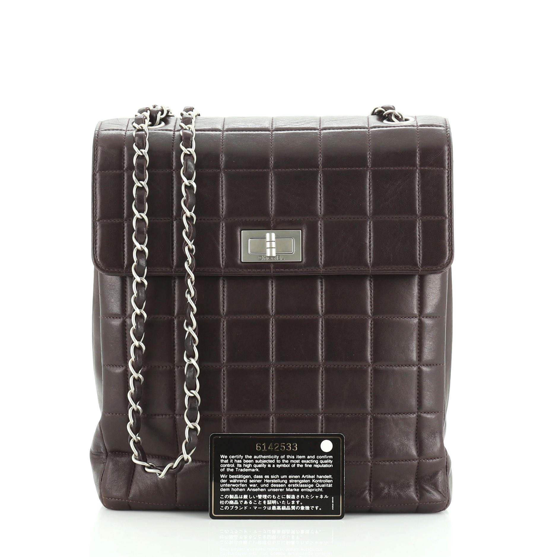 This Chanel Chocolate Bar Multipocket Flap Bag Quilted Leather Small, crafted from purple quilted leather, features woven-in leather chain strap, exterior pockets, and matte silver-tone hardware. Its mademoiselle turn-lock closure opens to a purple