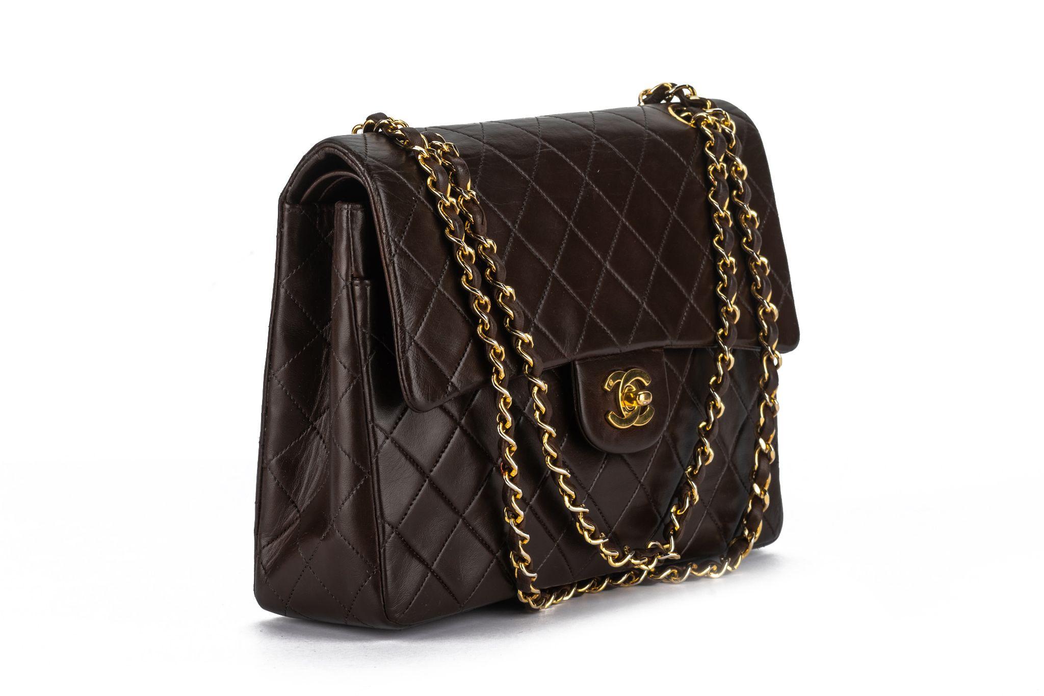 This Chanel shoulder bag features brown lambskin, an interlocking CC Logo & a quilted pattern, gold-tone hardware, chain-link shoulder straps, leather lining, turn-lock, flap, and snap closures at the front. Special style a little bit taller than