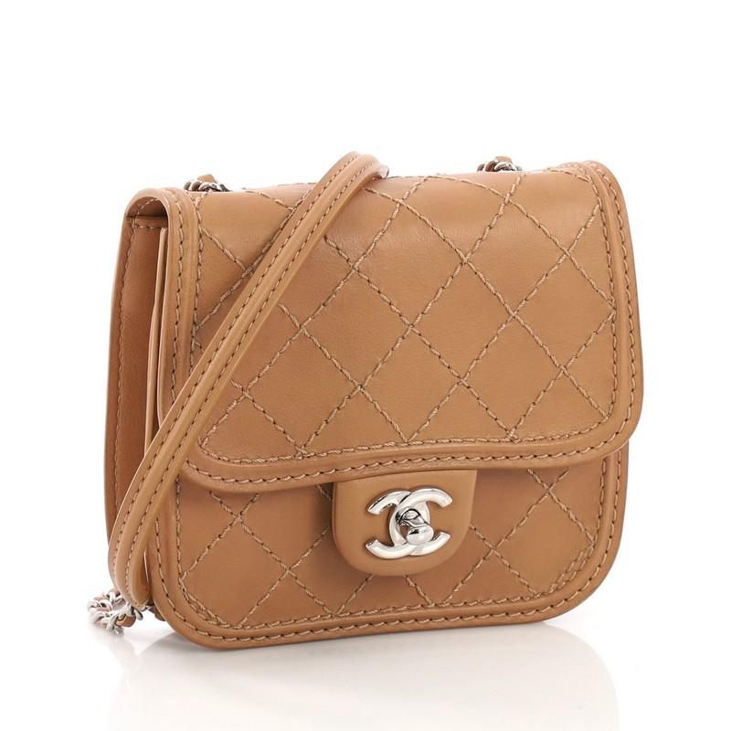 This Chanel Citizen Flap Bag Quilted Calfskin Mini, crafted from brown quilted calfskin, features woven-in leather chain strap with leather pad, exterior back slip pocket, and silver-tone hardware. Its CC turn-lock closure opens to a brown satin