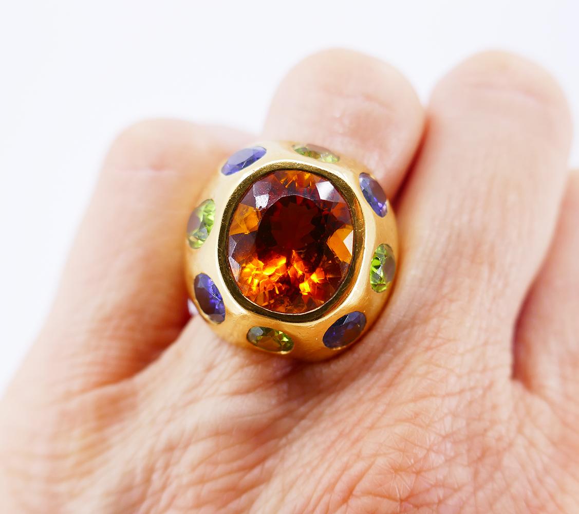 Anillo colorido, atrevido pero elegante, creado por Chanel en París en la década de 1980. Presenta un citrino ovalado de 7,09 quilates engastado en oro amarillo de 18 quilates y acentuado con cuatro peridotos ovalados (peso total de 3,68 quilates) y