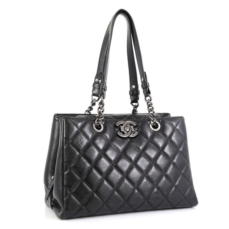 This Chanel City Rock Shopping Tote Quilted Goatskin Large, crafted in black leather, features chain-link shoulder strap, engraved CC push lock, and aged silver-tone hardware. Its push-lock closure opens to a black fabric interior with zip pocket.