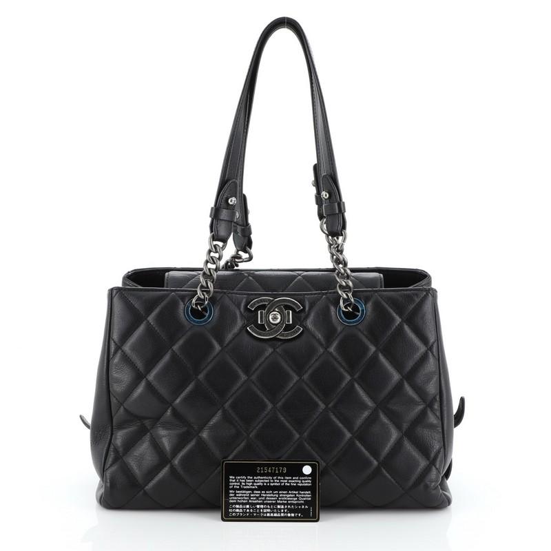 This Chanel City Rock Shopping Tote Quilted Goatskin Large, crafted in black leather, features dual chain and leather handles, CC closure stamped with '31 Rue Cambon Paris' and gunmetal-tone hardware. Its push-lock closure opens to a black fabric