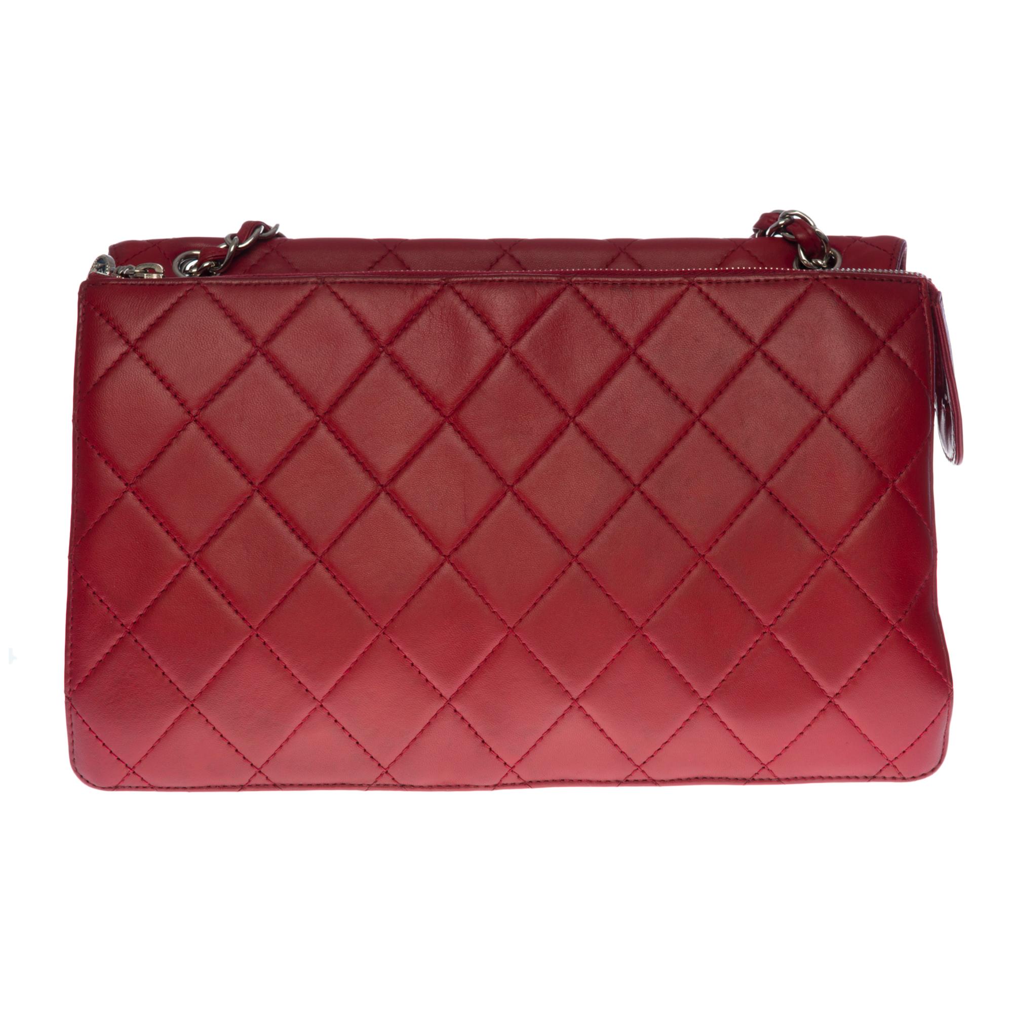 El amplísimo bolso Chanel 2.55 Maxi de piel acolchada roja, herrajes de metal plateado, 1 asa de cadena de metal plateado entrelazada con piel roja para asa de mano, bandolera o de hombro
Interior de lona roja
Cierre de solapa con broche giratorio