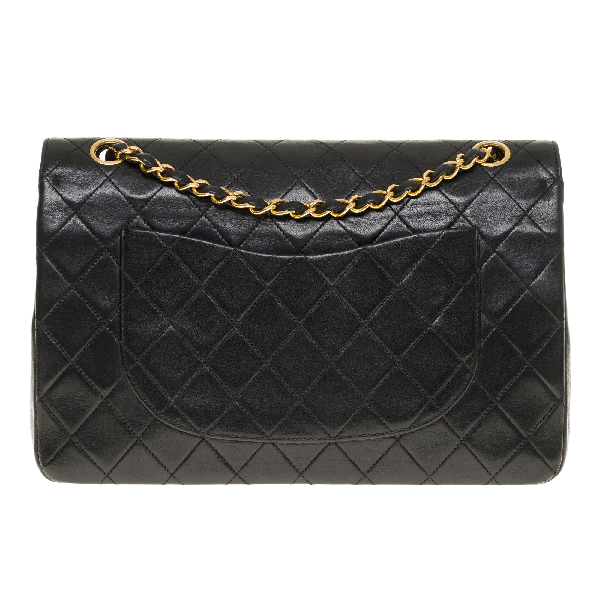 Beautiful Chanel Timeless/Classique 27cm handbag with double flap in black quilted lambskin leather, gold-tone metal hardware, a gold-tone metal chain handle interwoven with black leather allowing a hand or shoulder support.

Closure with gold metal