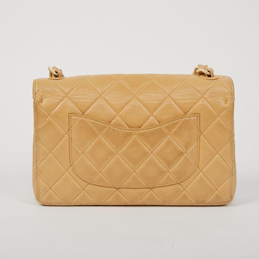 Limited series. This CHANEL second-hand bag is in beige smooth lambskin. The topstitching gives a quilted effect. The hardware is made of plastic with an ivory effect. The interior is beige leather with two flat pockets, one of which is zipped. Its