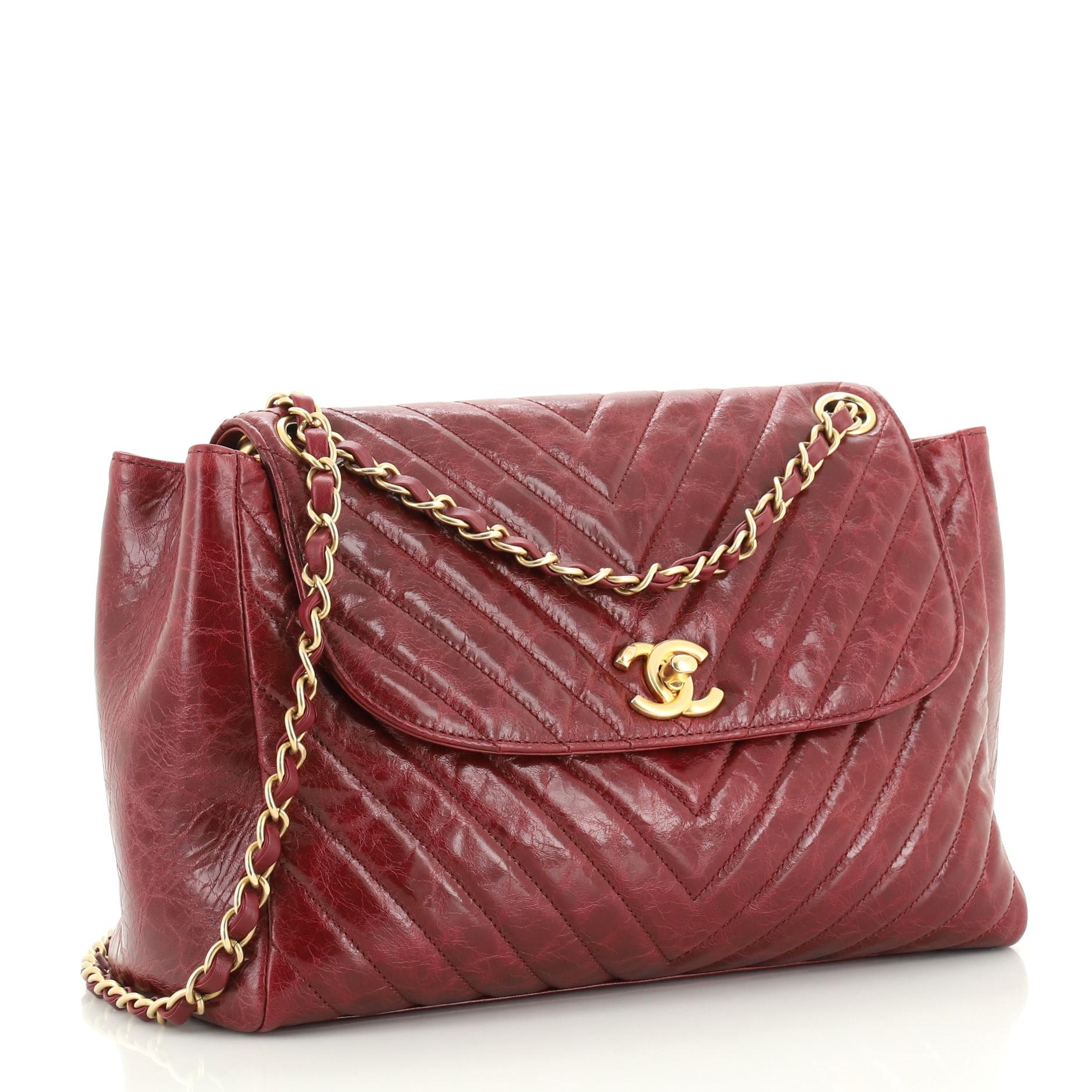 This Chanel Classic CC Hampton Flap Bag Chevron Aged Lambskin Medium, crafted from red chevron aged lambskin leather, features woven-in leather chain strap and aged gold-tone hardware. Its CC turn-lock closure opens to a red fabric interior.