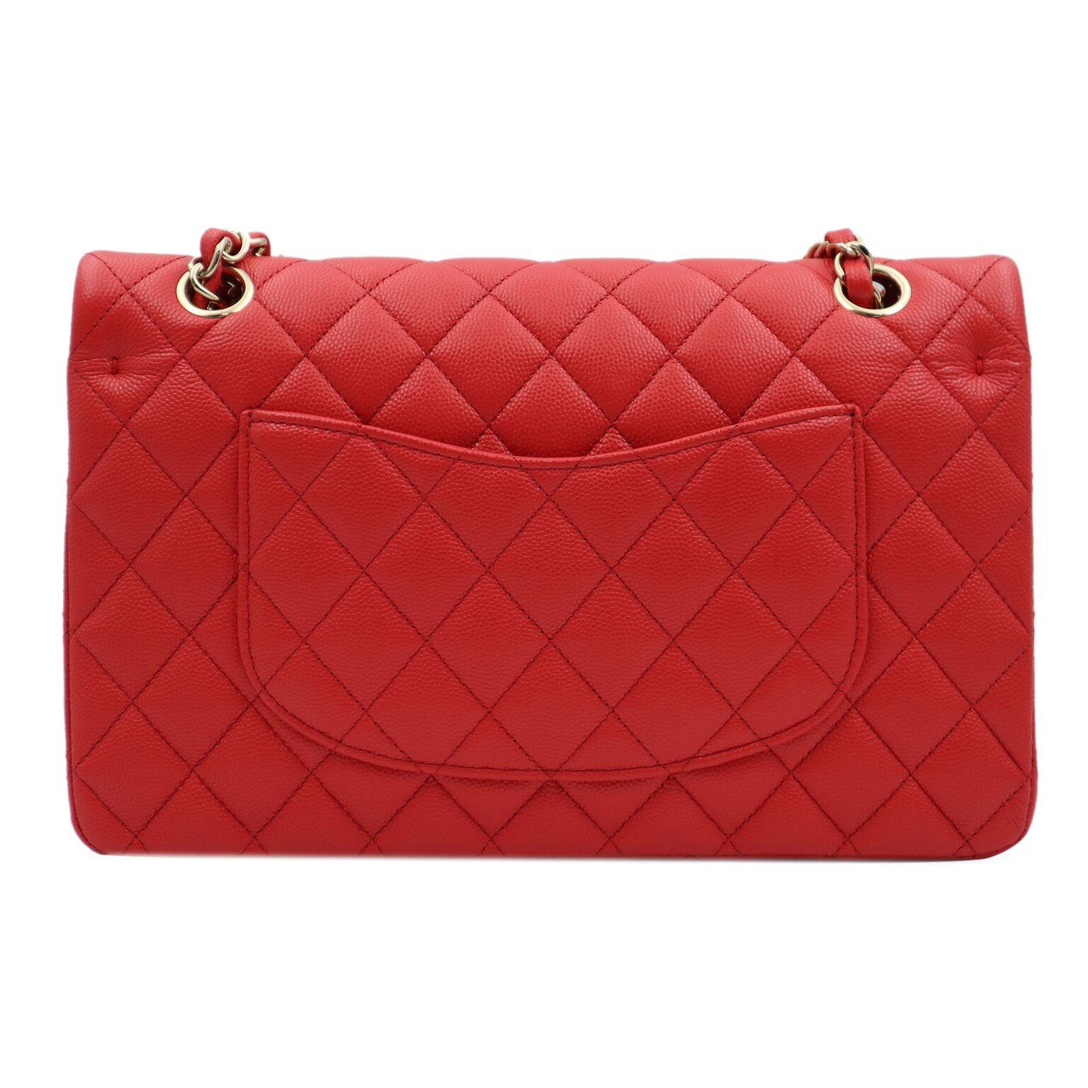 This chic Chanel classic medium flap bag is crafted of caviar leather in beautiful coral red color. The bag features a gold tone chain link leather threaded shoulder straps and a facing gold tone Chanel CC turn lock. The bag opens facing flap to a