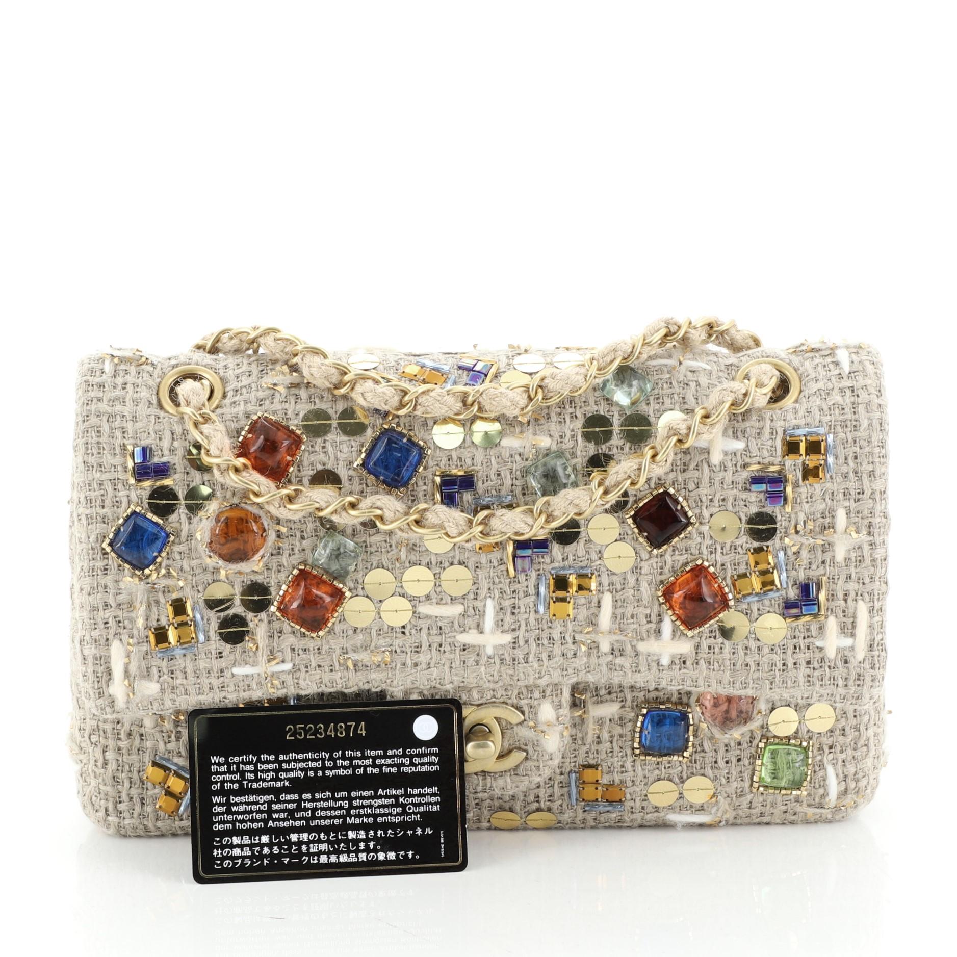 This Chanel Classic Double Flap Bag Embellished Woven Raffia Medium, crafted in neutral embellished woven raffia, features chain link strap, multicolor rhinestones and gold-tone hardware. Its double flap and CC turn lock closure opens to a neutral