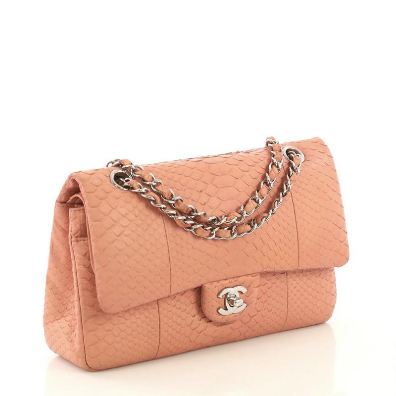 This Chanel Classic Double Flap Bag Python Medium, crafted from genuine pink python skin, features woven-in python chain strap, exterior back pocket, and silver-tone hardware. Its CC turn-lock closure opens to a pink leather interior with slip