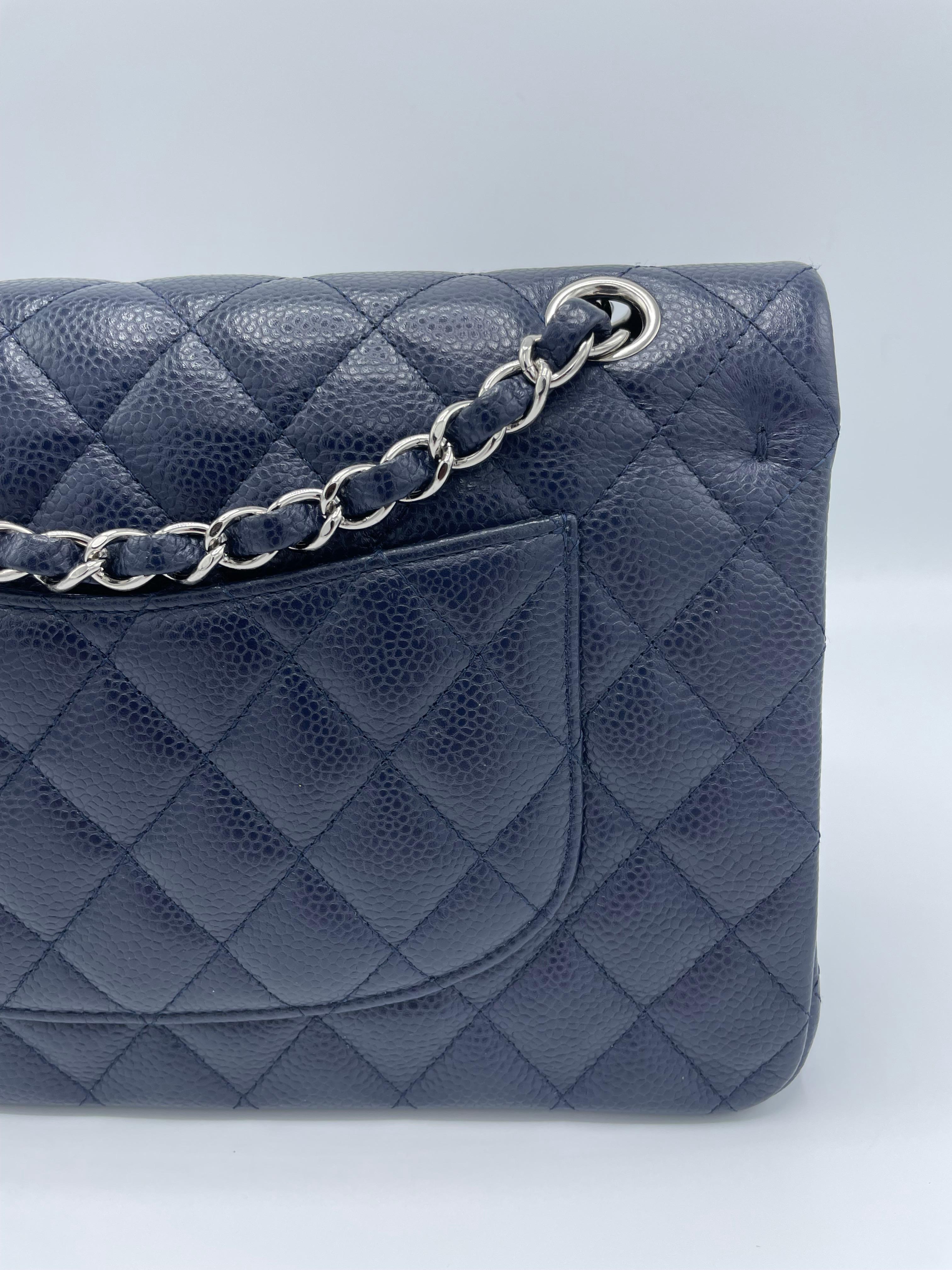 CHANEL Caviar Quilted Medium Double Flap Wallet in Navy. This classic flap bag is made of navy blue caviar leather that has been diamond quilted. It features leather shoulder straps with polished silver chain links strung through them, an external