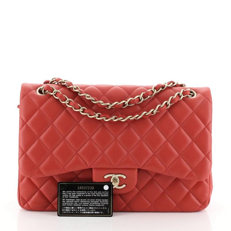 This Chanel Classic Double Flap Bag Quilted Lambskin Jumbo, crafted from red quilted lambskin leather, features woven-in leather chain strap, exterior back pocket and matte gold-tone hardware. Its double flap and frontal CC turn-lock closure opens