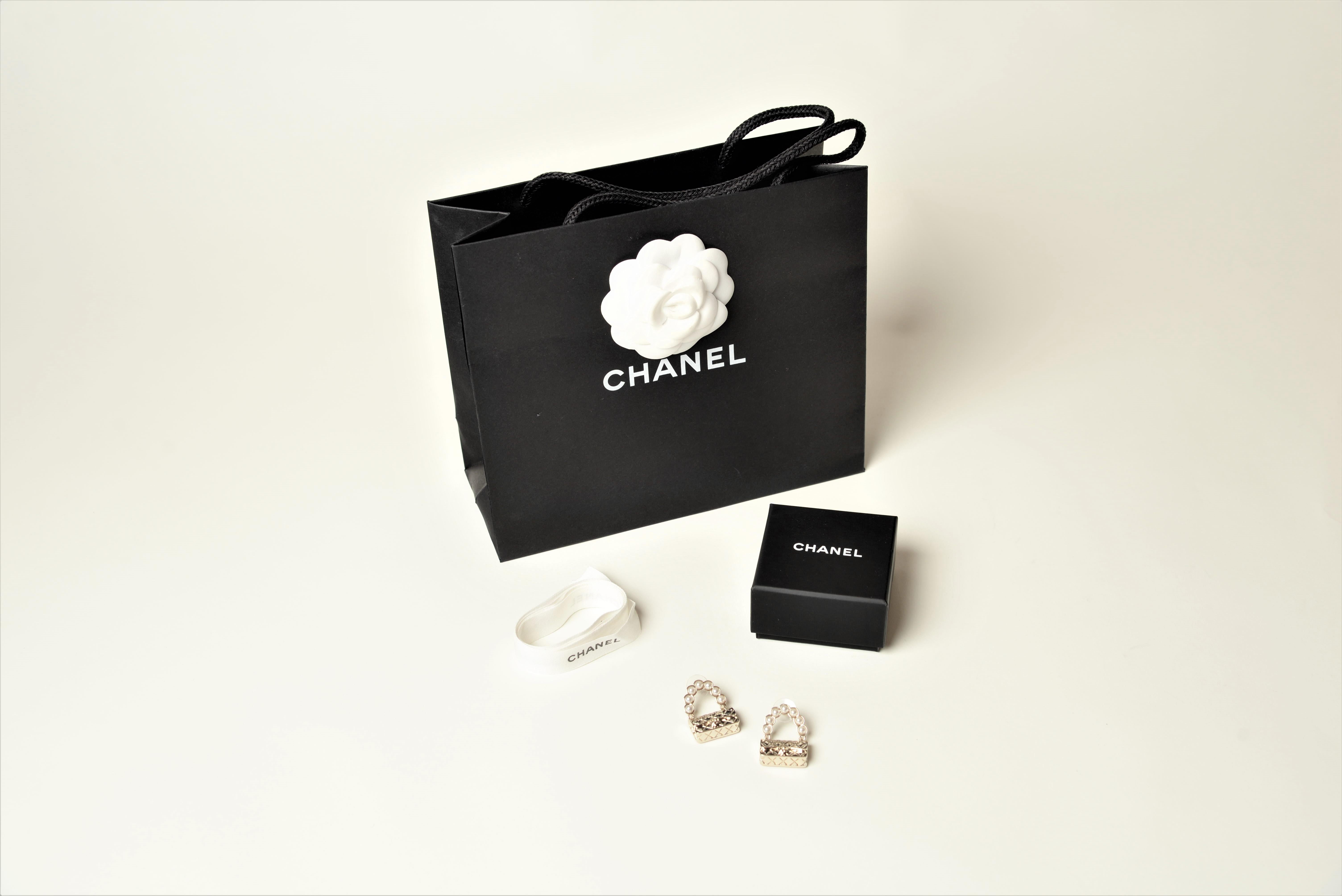 From the collection of SAVINETI we offer this Chanel Classic Flap Bag Earrings:
-	Brand: Chanel
-	Model: Classic Flap Bag Earrings
-	Year: 2021
-	Condition: Very Good (as new)
-	Materials: Champagne Metal and Glass Pearls
-	Extras: comes with the